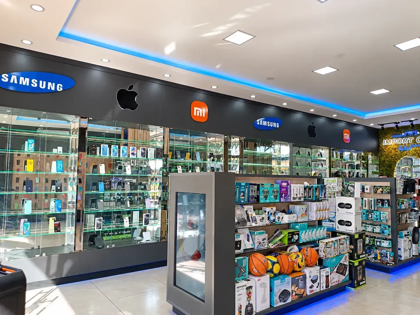 Parede verde com letreiro neon Import Cell, espelho e vitrines de perfumes e acessorios